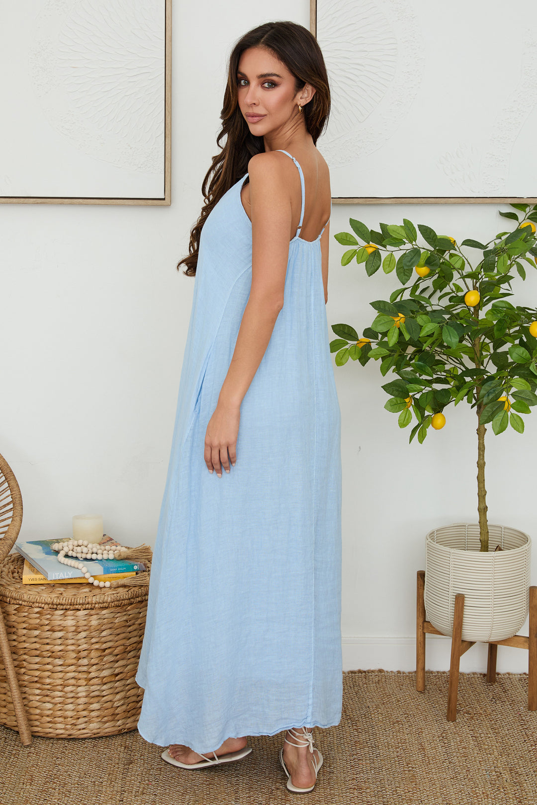 The Bella Breeza linen maxi dress with thin straps, open back, and flowy silhouette in light blue.