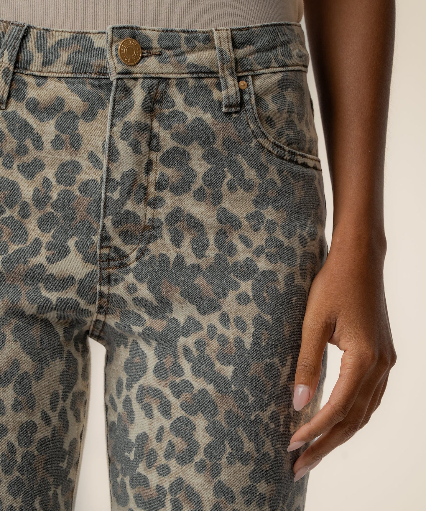 Kut Kelsey High Rise Ankle Flare jeans close-up showing tan and gray leopard print denim with gold hardware waist button.