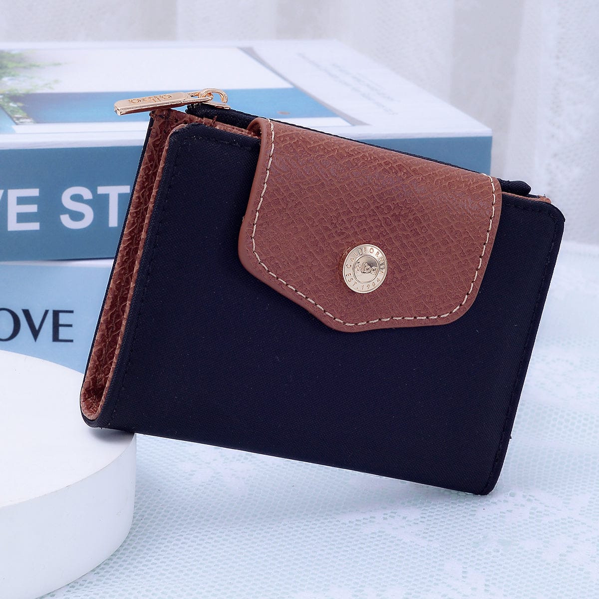 MiMi Wholesale Stephie Nylon Snap Bifold Wallet in black with brown leather flap, gold snap button, and zipper detail, front view