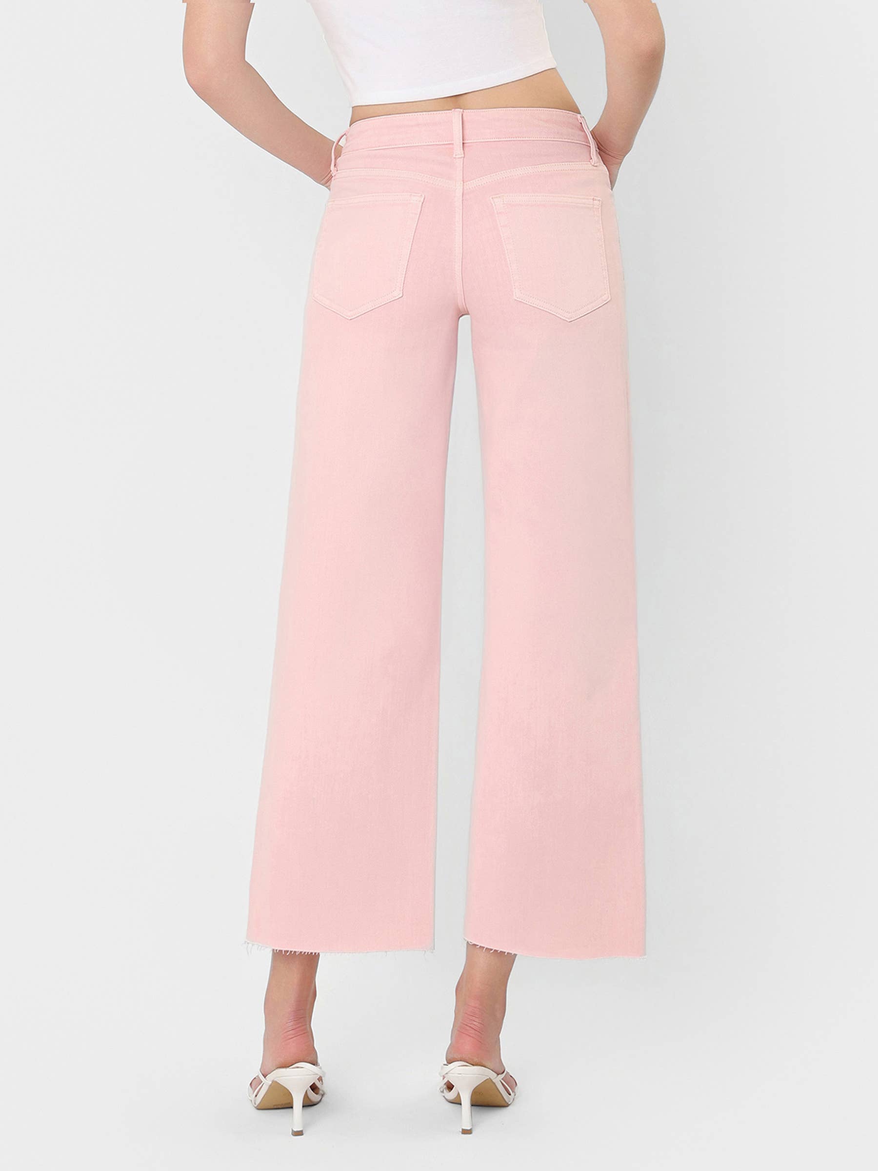 High Rise Crop wide leg bubblegum pink jeans with raw hem, back pockets, and white heel sandals.