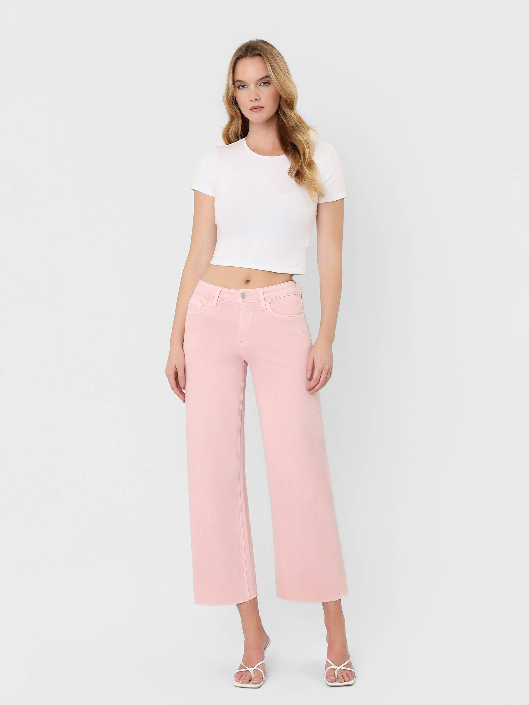Model wearing High Rise Crop wide leg cropped jeans in bubblegum pink with raw hem detail and white crop top.