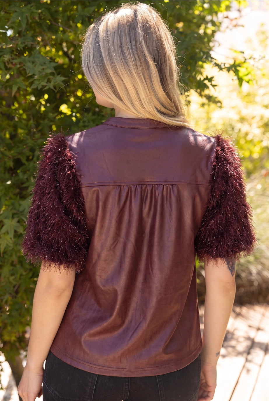 The Faux Feather Top Burgundy featuring a faux leather back with fluffy feather-textured short sleeves.