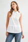 Caroline sleeveless white collared button-front shirt top with layered hem detail, styled with blue jeans.