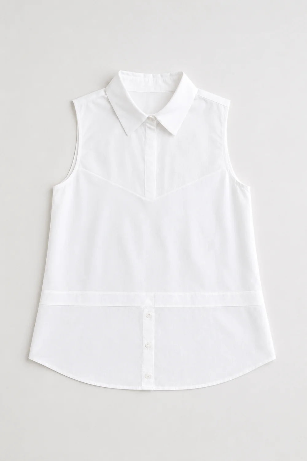 Caroline sleeveless white button-front collared shirt with curved hem and structured bodice paneling.