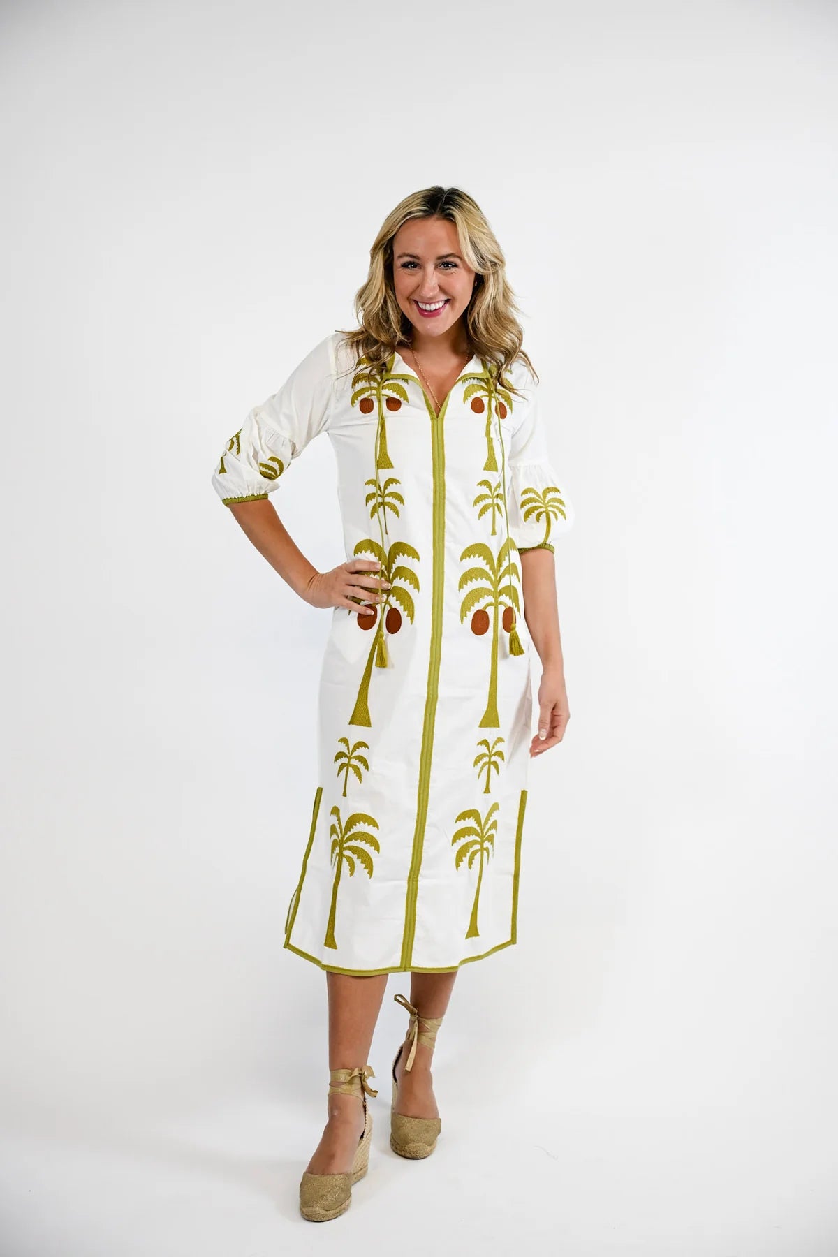 Victoria Dunn Esme white midi dress with olive green palm tree embroidery, tassel ties, and three-quarter sleeves.