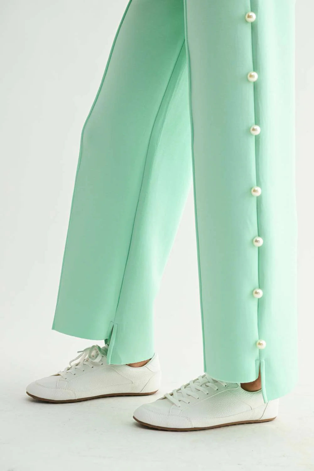 Joh Apparel Farrah French Scuba wide-leg mint pants with pearl button side detail, paired with white sneakers.