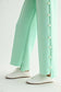 Joh Apparel Farrah French Scuba wide-leg mint pants with pearl button side detail, paired with white sneakers.