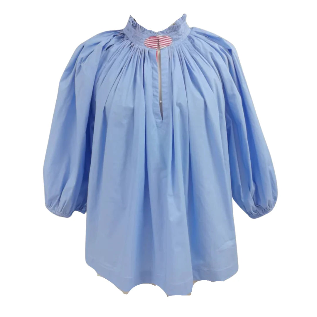 Caryn Lawn Camille Top in periwinkle blue with gathered ruffle neckline, balloon sleeves, and pink striped keyhole detail, flat lay.