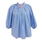 Caryn Lawn Camille Top in periwinkle blue with gathered ruffle neckline, balloon sleeves, and pink striped keyhole detail, flat lay.