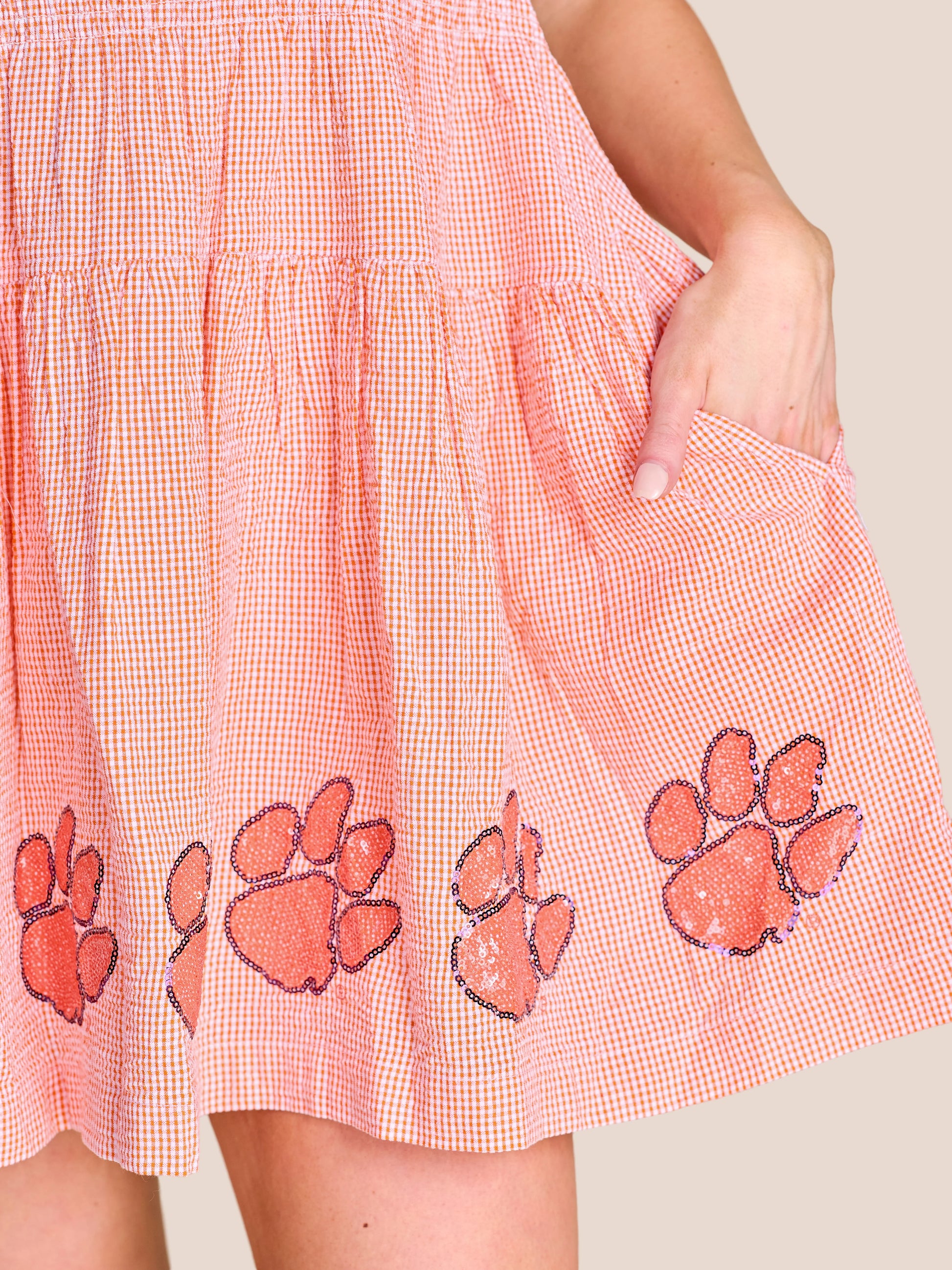 Stewart Simmons Good Sport Seersucker Dress Clemson close-up showing orange gingham fabric, sequin paw print hem, and side pocket.