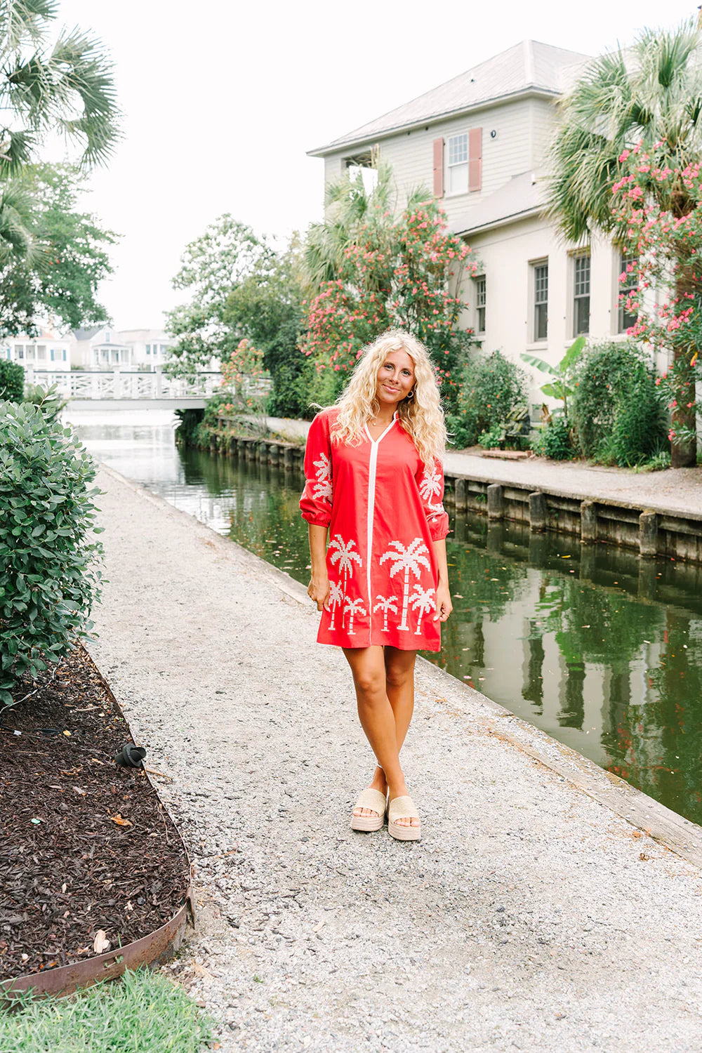 Victoria Dunn Presley red shift dress with white palm tree embroidery, worn with neutral platform sandals outdoors.