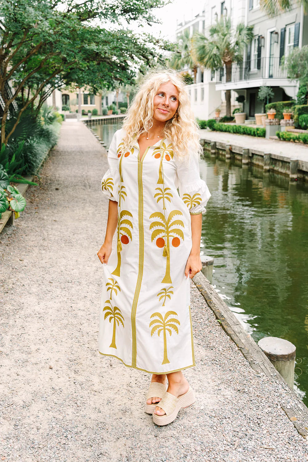 Victoria Dunn Esme white maxi dress with gold palm tree embroidery, worn with woven platform sandals.