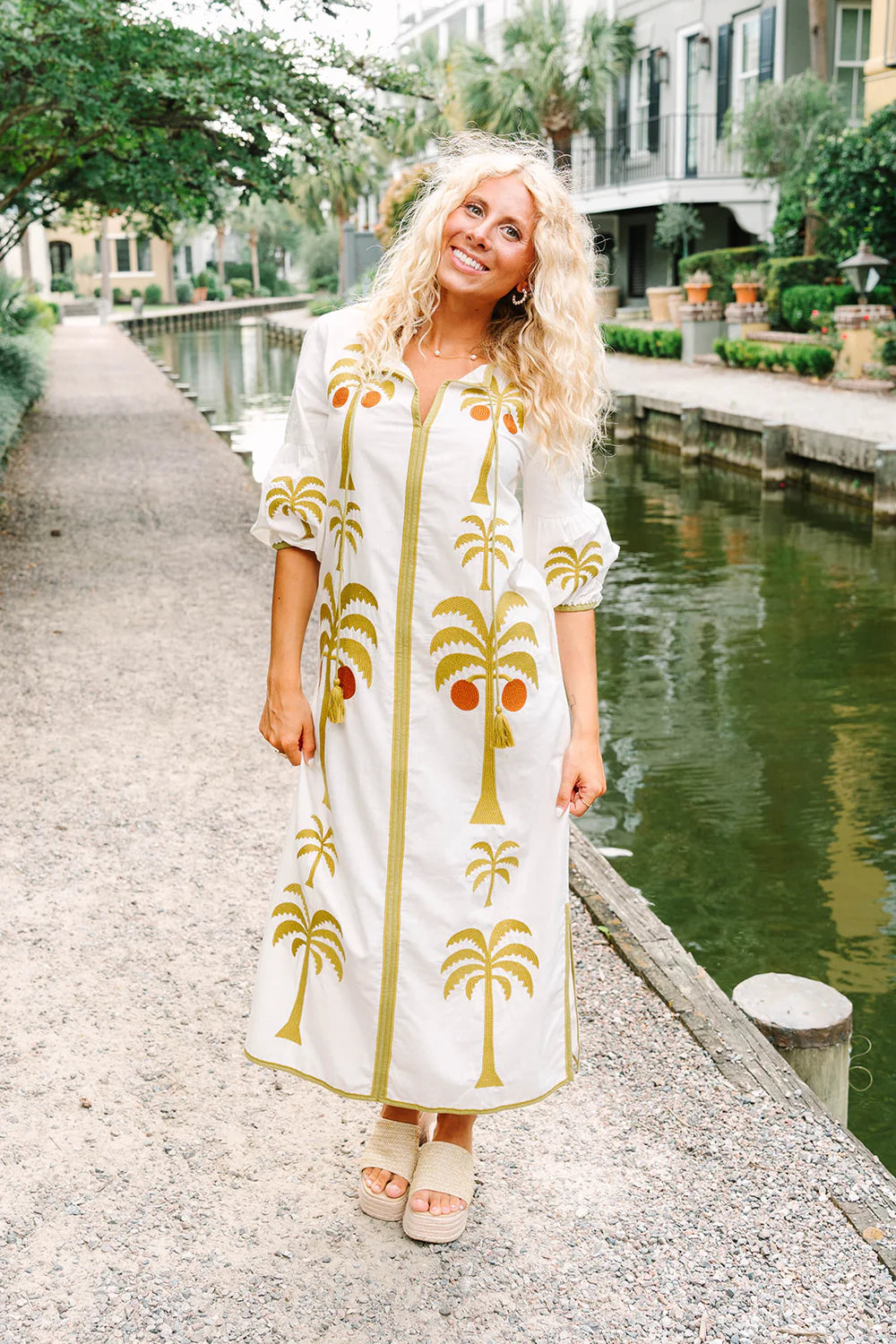 Victoria Dunn Esme white maxi dress with gold embroidered palm trees, puff sleeves, and tassel tie neckline.