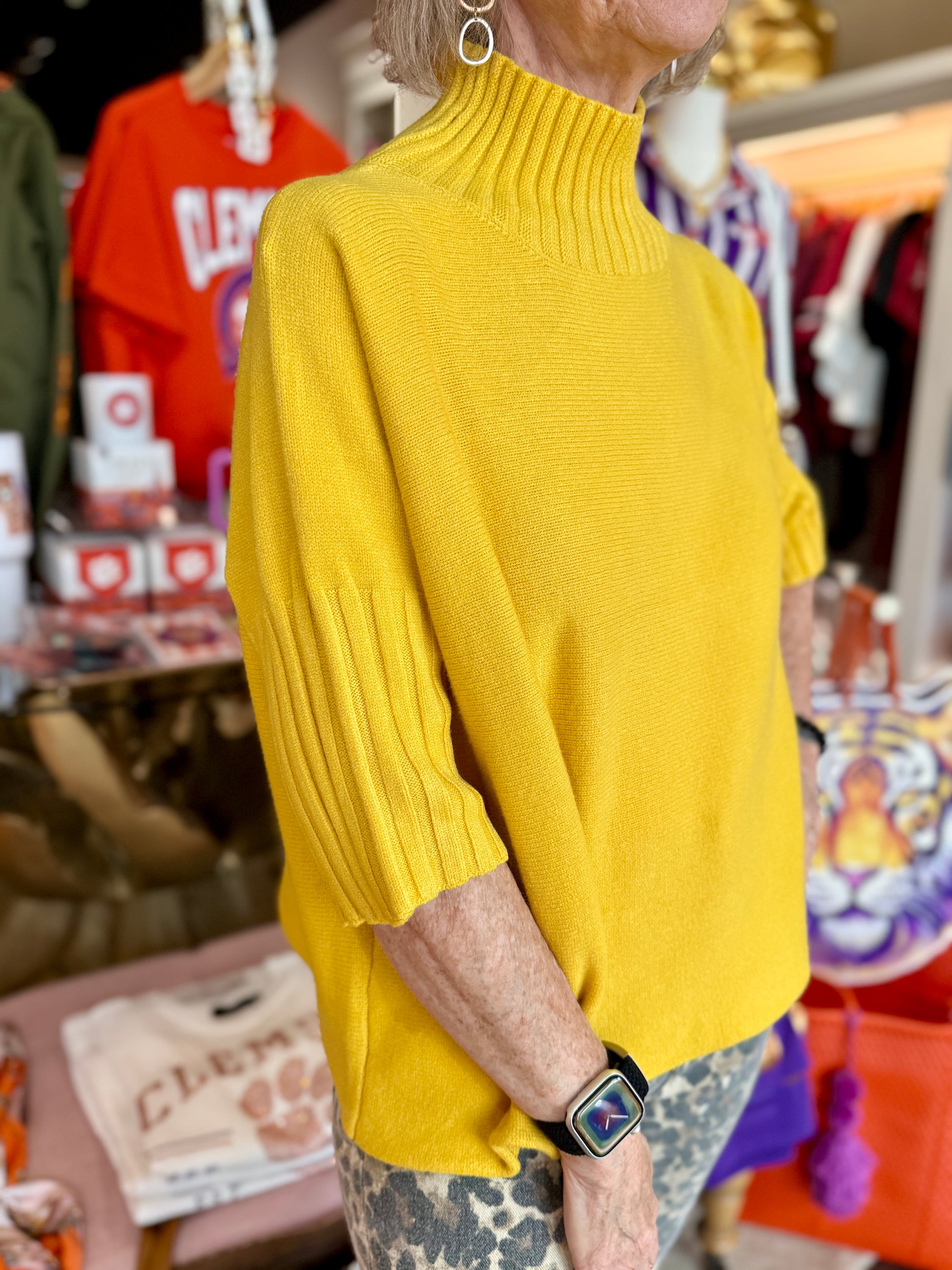 The Maple Mockneck Sweater in mustard yellow with ribbed collar, elbow-length sleeves, and relaxed fit.