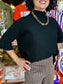The Maple Mockneck Sweater in black with ribbed cuffs and mock turtleneck collar, styled with houndstooth pants.