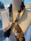 Ready To Wear magnetic scarf with baroque gold print, tied elegantly on mannequin with pearl accent.