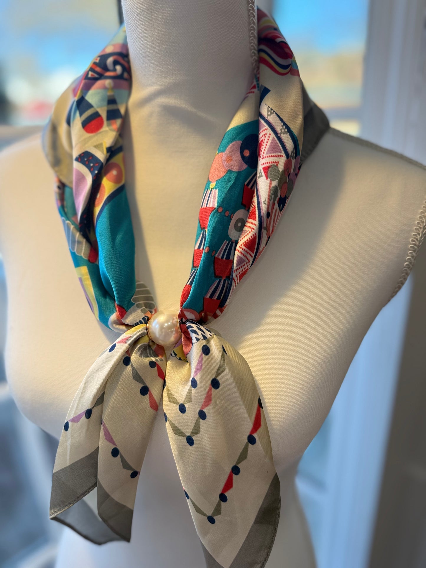Ready To Wear magnetic scarf with colorful geometric print, tied with a pearl accent on mannequin.