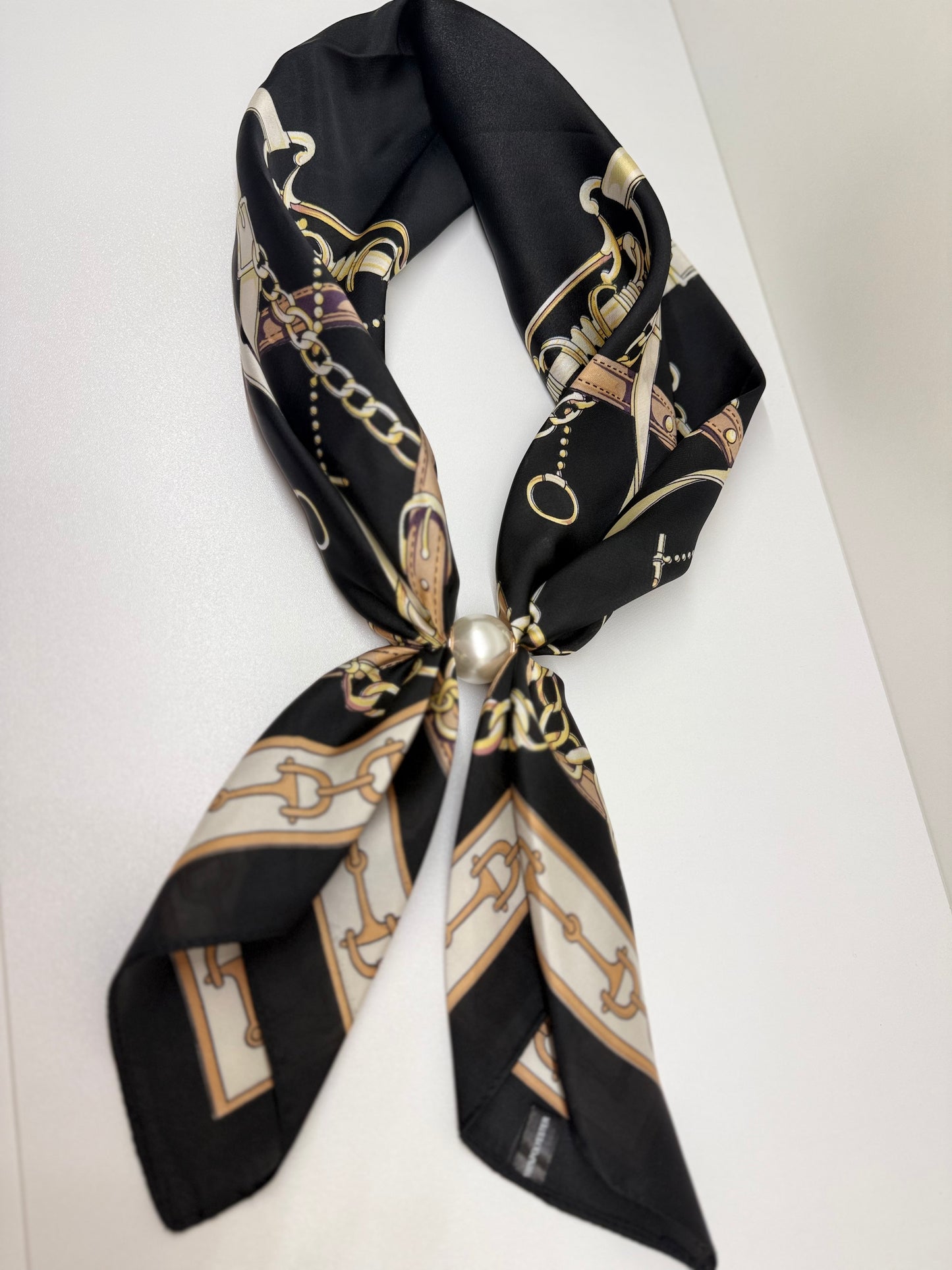 Ready To Wear black silk scarf with equestrian chain print, tied with a pearl magnetic closure.