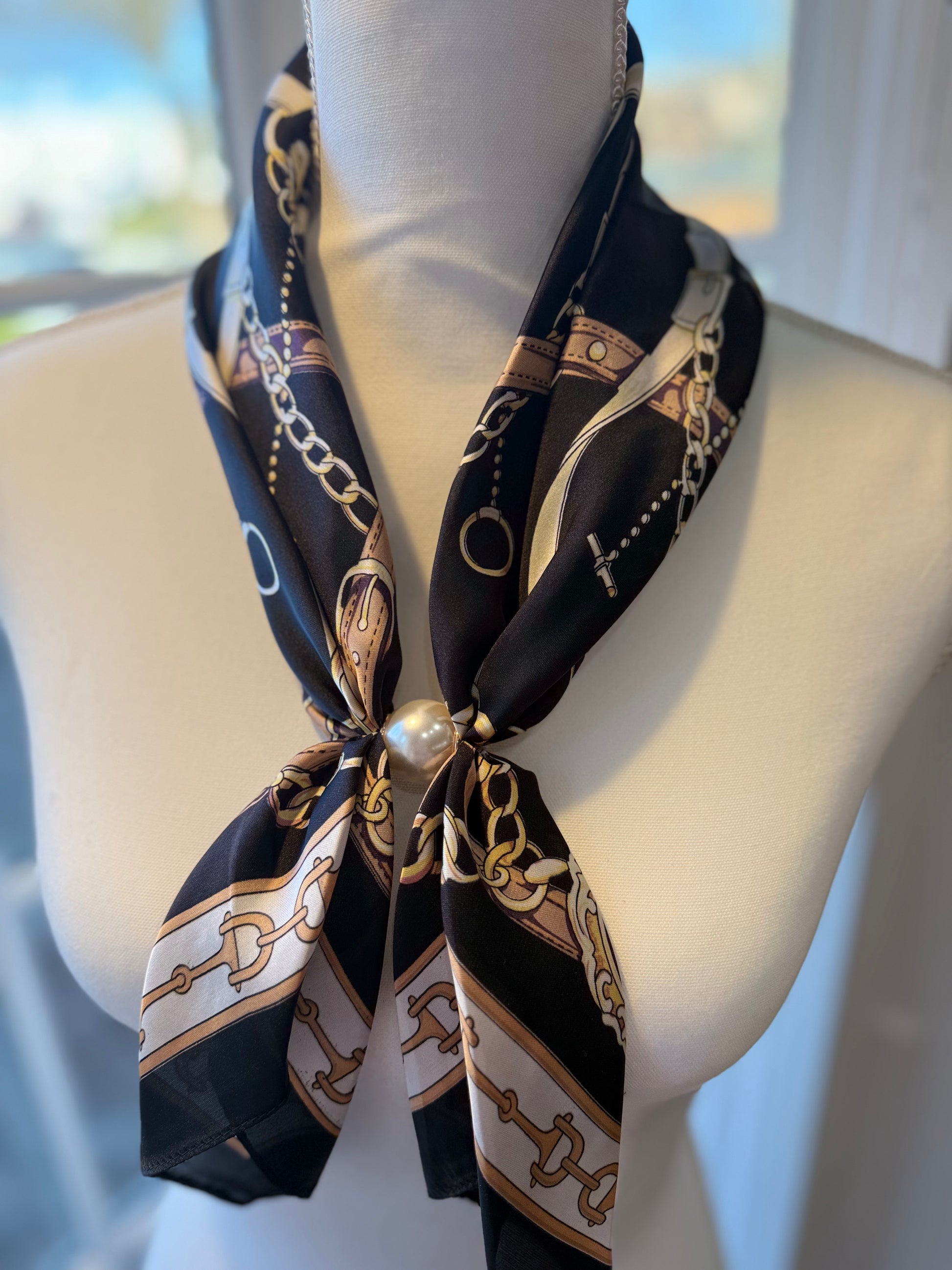 Ready To Wear magnetic scarf with chain print draped on mannequin, secured with large pearl accent.