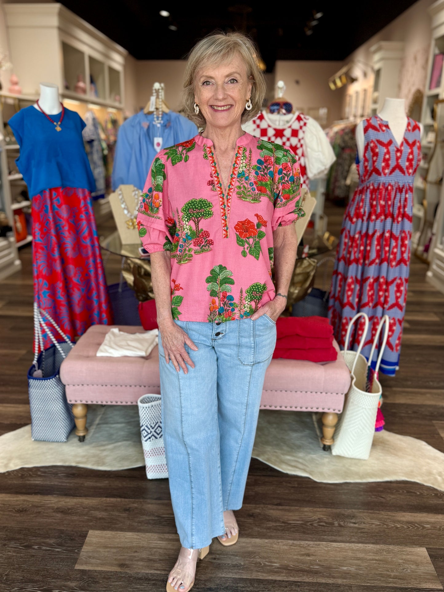 Maude Vivante Raya Top in pink with green and red floral garden print, V-neckline, puff sleeves, worn with wide-leg jeans.