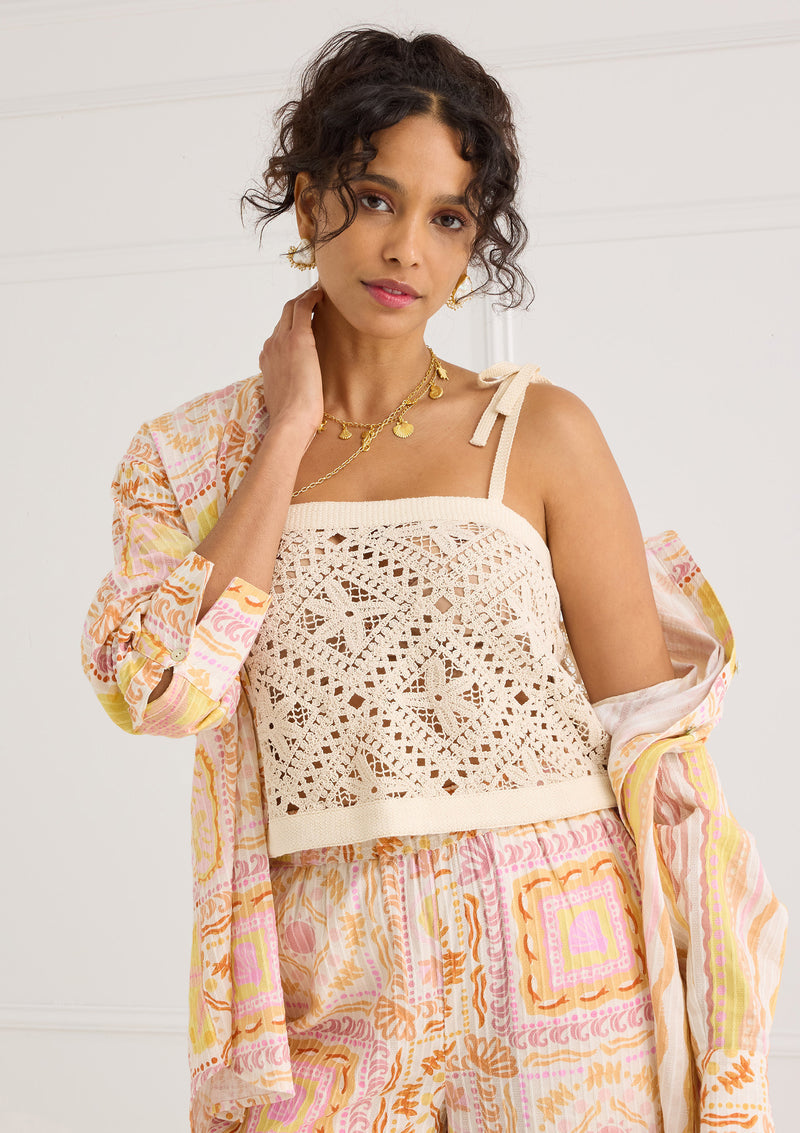 Alivia Kendra Top Seastar Crochet in cream, open-knit pattern, tie straps, worn by model with printed skirt and jacket.
