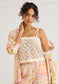 Alivia Kendra Top Seastar Crochet in cream, open-knit pattern, tie straps, worn by model with printed skirt and jacket.