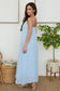 The Bella Breeza linen maxi dress with thin straps, open back, and flowy silhouette in light blue.