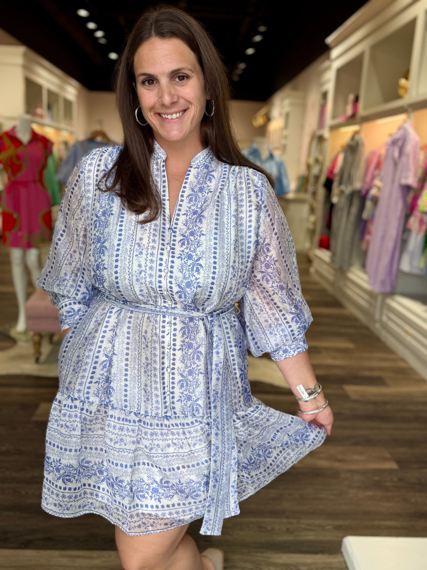 Joy Joy Porcelain Garden Dress featuring blue and white floral print, belted waist, flutter sleeves, and tiered hem.