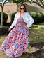 Printed Tiered Maxi Dress with bold geometric pattern, smocked bodice, worn with white denim jacket outdoors.
