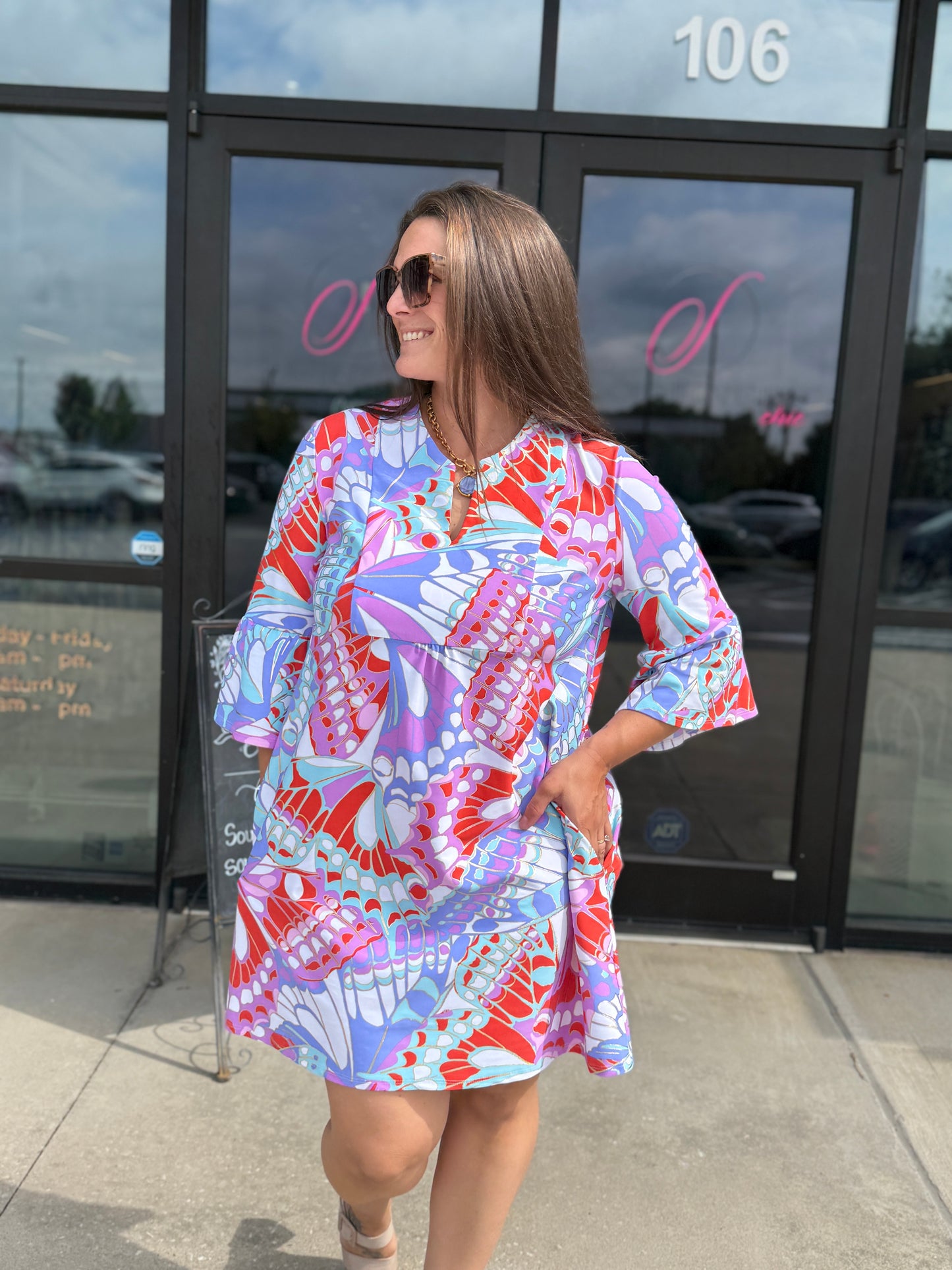 Jude Connally Kerry dress featuring a vibrant butterfly mosaic print with bell sleeves, worn above the knee.