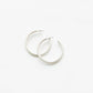 Michelle McDowell Heather Earrings in silver — flat lay of two matte silver tube hoop earrings with post backs.