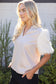 The Faux Feather Top Cream featuring a V-neckline, feathered short sleeves, and a relaxed knit body.