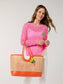 Lyra Tote woven rattan tote bag with orange leather trim, handles, and banana charm keychain.