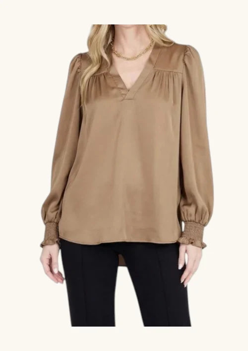 Joy Joy V-Neck Blouse Cafe in warm tan satin, featuring gathered shoulders, blouson sleeves, smocked cuffs, worn by model with black pants.