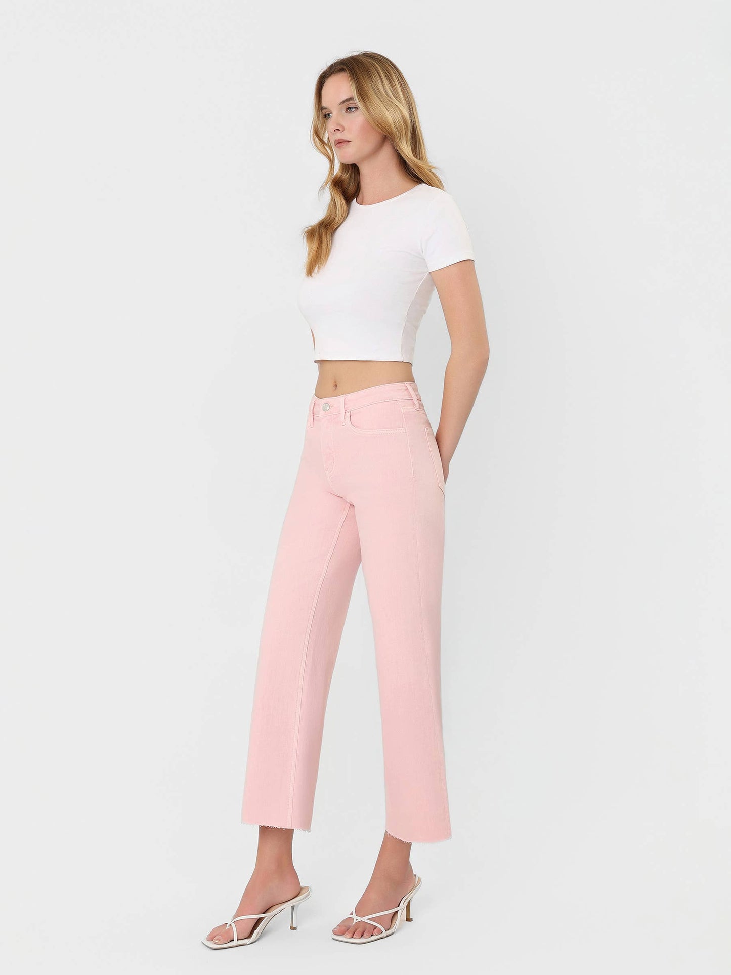 High Rise Crop wide leg jeans in bubblegum pink, styled with white crop top and strappy heels.