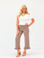 EE Some Gingham Ruffle Hem Pants in brown check print with ruffle ankles, styled on a model with a white off-shoulder top and tan heels.