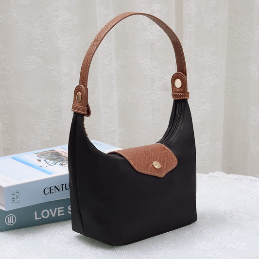 MiMi Wholesale HM780 Nora Nylon Bag in black with tan leather handle and flap detail, styled beside books on a white surface.
