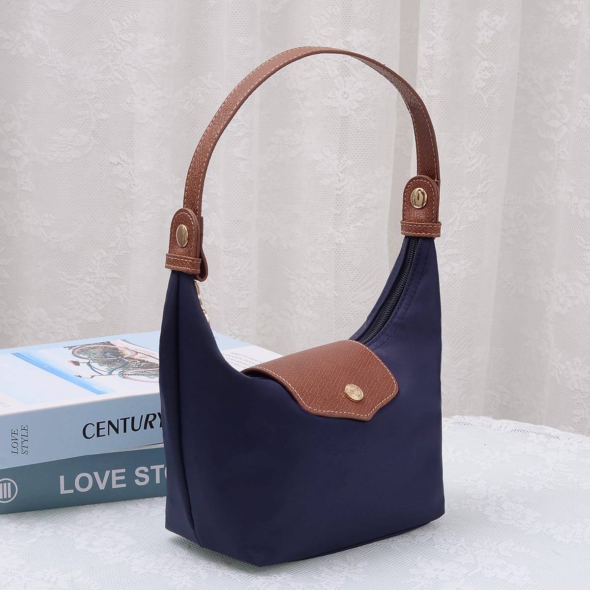 MiMi Wholesale Nora Nylon Bag HM780 in navy blue with tan leather handle and front pocket, angled view on white surface