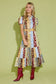 Alden Adair Luna Dress Golden Bouquet: model wearing patchwork floral midi dress with belt and red cowboy boots, front view.