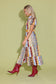 Alden Adair Luna Dress Golden Bouquet: model wearing patchwork floral midi dress with red croc-embossed knee-high boots, side view.