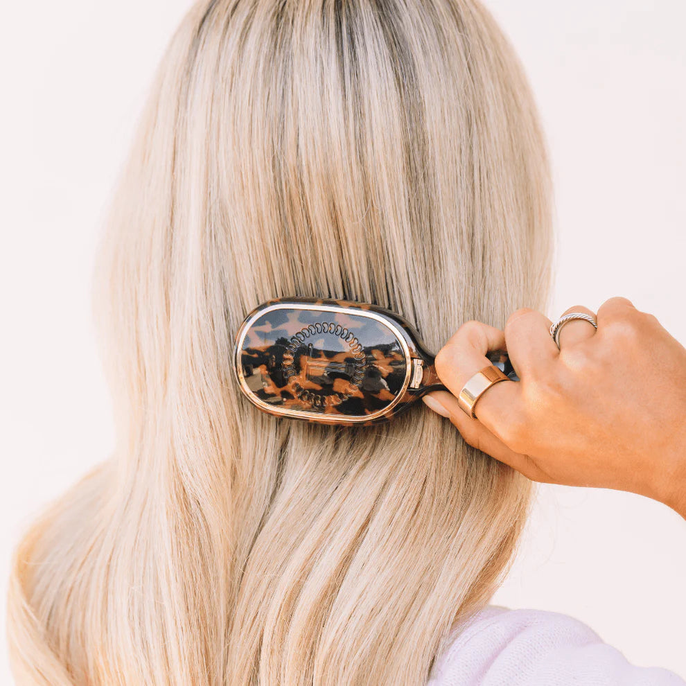 Teleties Mini Detangler Hair Brush in tortoise pattern being used to brush long blonde hair.
