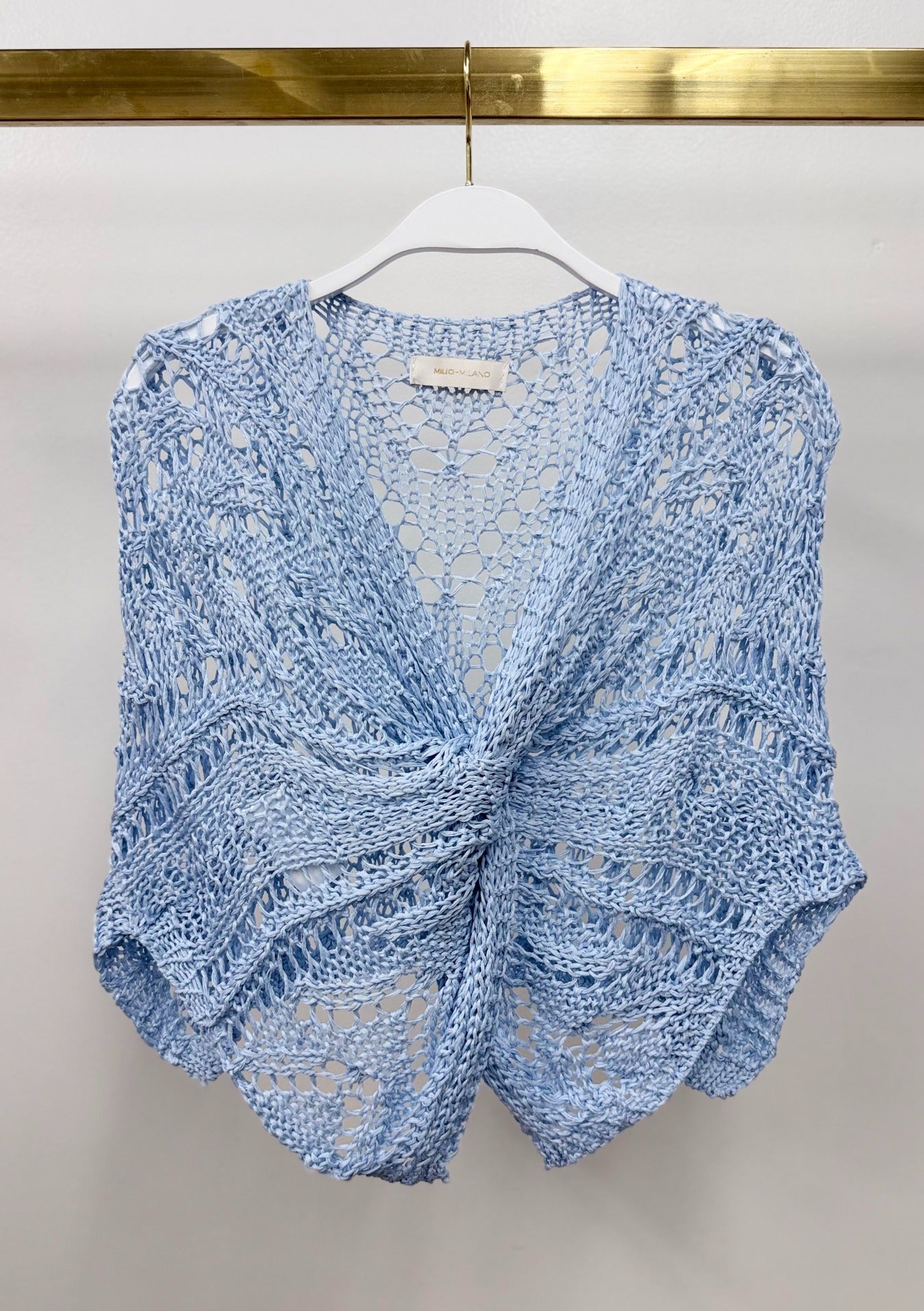 Milio Milano light blue open-weave crochet knit poncho with front twist knot detail, displayed on white hanger.